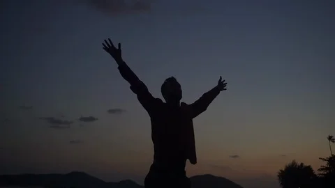 Young man silhouette on the beach sunset celebrating success Stock Footage 107445092