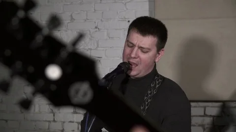 Young man singing to the microphone and playing the guitar on rehearsal Stock Footage 74208056