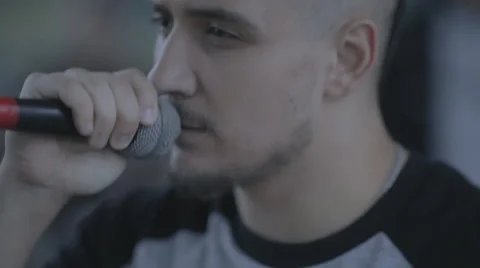 A young man singing into a microphone from the stage at a concert Stock Footage 57696336