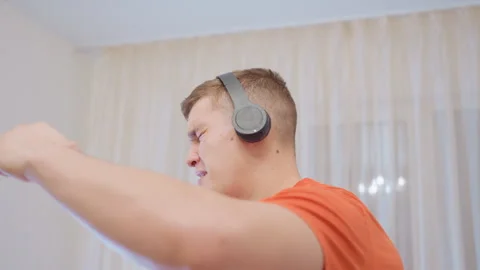 Young Man Singing With Mop Handle While Listening To Music On Headphones Stock Footage 319916103