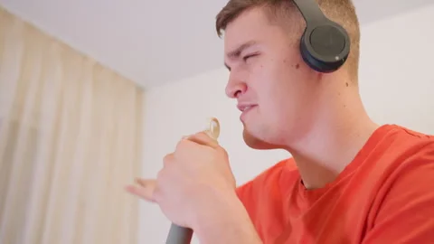 Young Man Singing Into Mop Handle With Headphones On Stock Footage 319917591