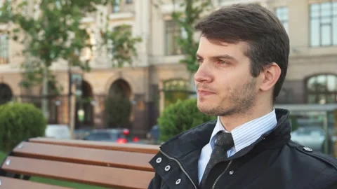Young man sipping coffee on a bench, lost in thought Stock Footage 311935688