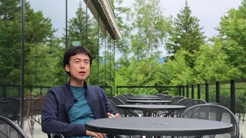 Young man sips drink at outdoor cafe table Stock Footage 340237324