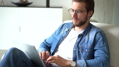Young man sit in armchair use laptop, working distantly using wireless tech 스톡 동영상 155331426