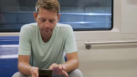 Young man sit in empty carriage on a subway train and using smartphone for Stock Footage 256647467
