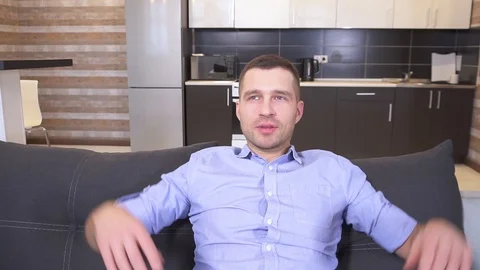 Young man sit on sofa and leaning with head back to edge of sofa. Keep hands Stock Footage 128911677