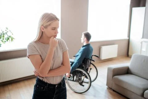 Young man sit with special needs sit on wheelchair and look on window. Woman Stock Photos