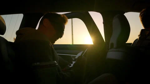 Young man sits in the back seat of a car at sunset and fastens his seat belt Stock Footage 279851897