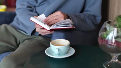 Young man sits behind a glass in a cafe reading a book. Stock Footage 250951561