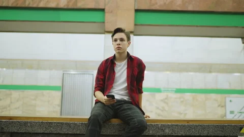 A young man sits on a bench in the subway, looks at the incoming train, gets up. Stock-Footage 209210245