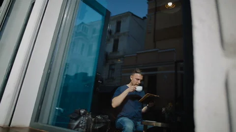 The young man sits in cafe and works with the tablet Stock Footage 62549586