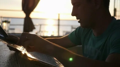 A young man sits in a cafe and selects food from the menu, against the Stock Footage 79928197
