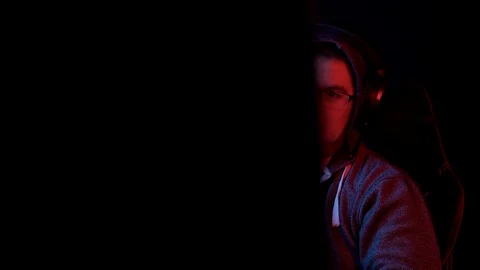 A young man sits at a computer and expresses respect. The man in the hood looks Stock Footage 125776794