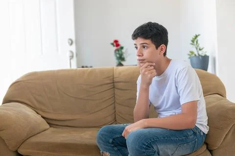 A young man sits on a couch, looking at the camera Stock Photos