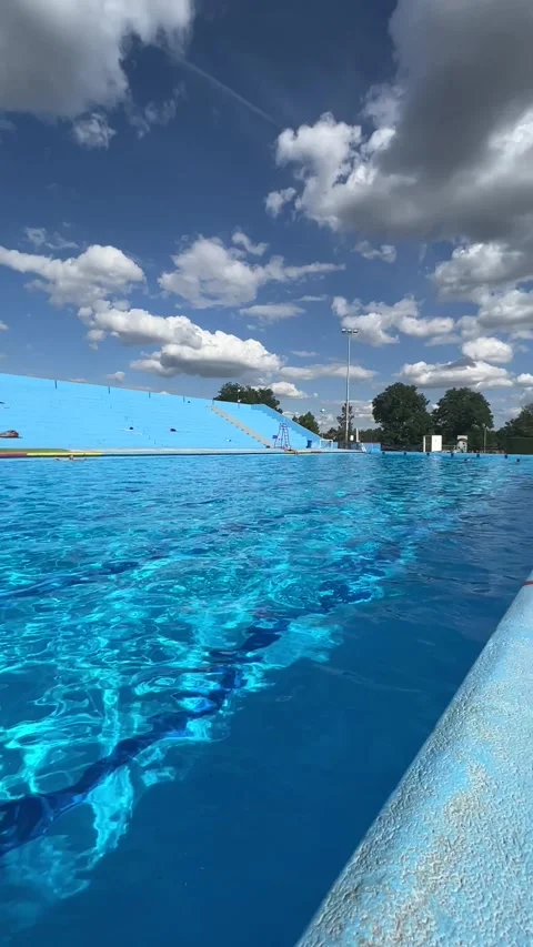 A young man sits on the edge of the pool with his legs dangling into it Stock Footage 247625297