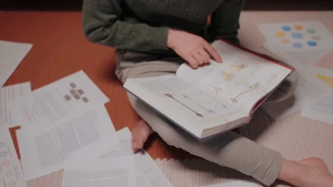Young man sits on the floor surrounded by papers and notes, listens music Stock Footage 164381388
