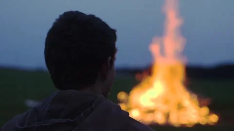 Young Man Sits in Front of a Bonfire Stock Footage 48690093