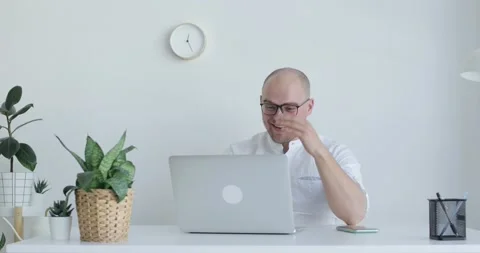 Young man sits in front of a laptop and communicates with someone. Front view. Stock Footage 154015089