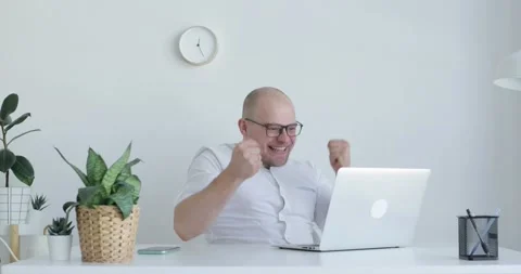 Young man sits in front of a laptop. He is surprised and joyful. Side view. Stock Footage 154015162