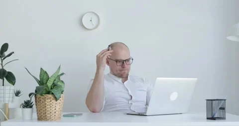 Young man sits in front of a laptop and thinks. Front view. Stock Footage 154032149