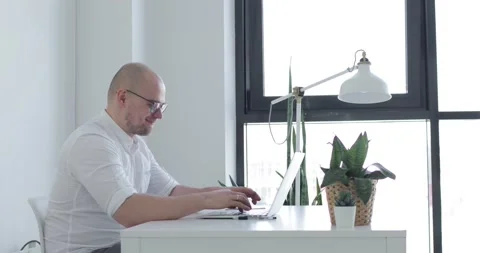 Young man sits in front of a laptop and chatting. Side view. Stock Footage 154237686