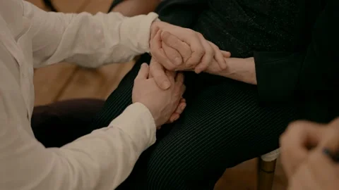 A young man sits next to an elderly woman and holds her in his hands. Video stock 238532625