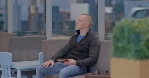 Young man sits with a notebook in his hands while waiting, meeting at a car Vídeo Stock 134420505