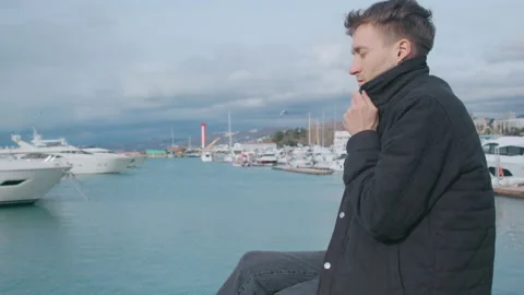 Young man sits on the pier and warms himself up Stock Footage 151077845