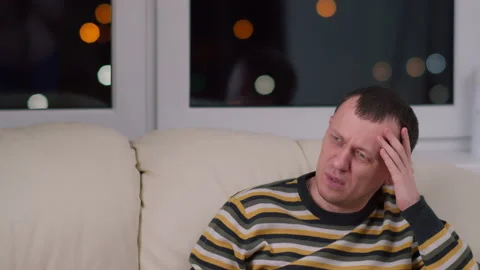 Young man sits on the sofa at night and watches news, negative emotions Stock Footage 133588683