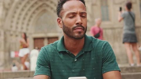 Young man sits on the steps of Sagrada Familia in Barcelona and looks around Stock Footage 227097510
