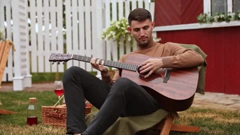 Young man sits at the table and plays the guitar Stock Footage 252043004