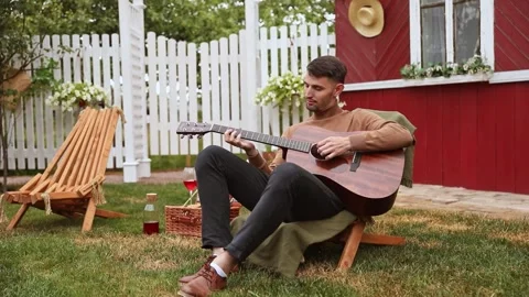 Young man sits at the table and plays the guitar Stock Footage 252151416