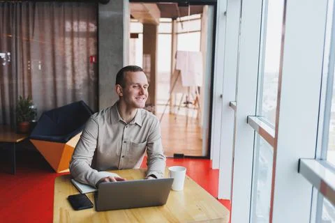 A young man sits at a table and opens a laptop computer while studying online Stock Photos
