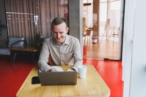A young man sits at a table and opens a laptop computer while studying online Stock Photos