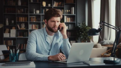 Young man sits at table with laptop in home office Stock Footage 260923102