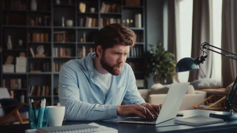 Young man sits at table with laptop in home office Stock Footage 260924061