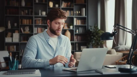 Young man sits at table with laptop in home office Stock Footage 260924590