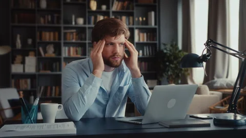 Young man sits at table with laptop in home office Video stock 260931929