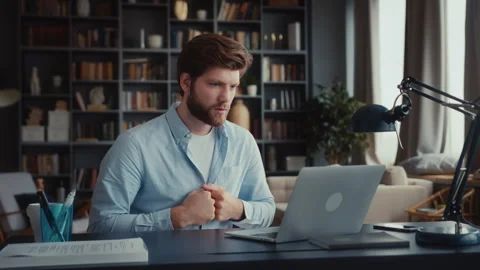Young man sits at table with laptop in home office Stock Footage 260935715
