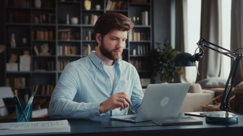 Young man sits at table with laptop in home office Stock Footage 260935972