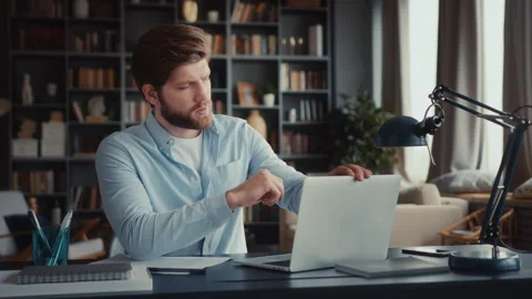 Young man sits at table with laptop in home office Stock Footage 260937168