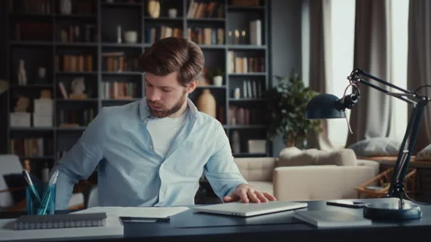 Young man sits at table with laptop in home office Stock Footage 260937382