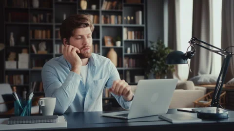 Young man sits at table with laptop in home office Stock Footage 260937552