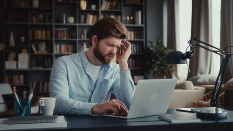Young man sits at table with laptop in home office Stock Footage 260937983