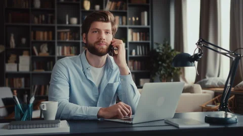 Young man sits at table with laptop in home office Video stock 260938022