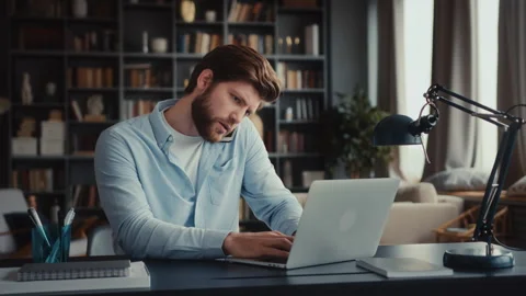 Young man sits at table with laptop in home office Stock Footage 260939067