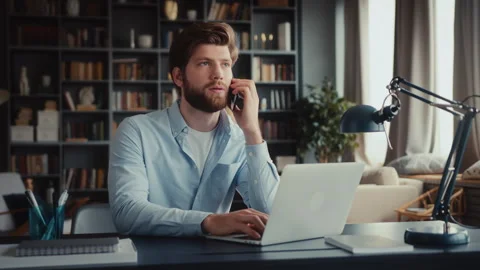 Young man sits at table with laptop in home office Video stock 260939637