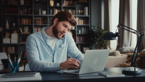 Young man sits at table with laptop in home office Stock Footage 260939847