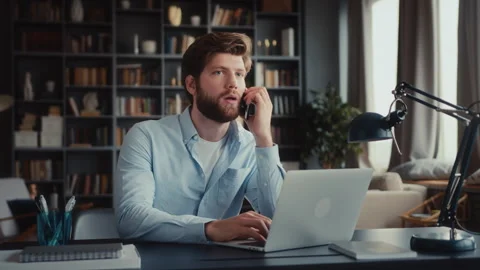 Young man sits at table with laptop in home office Stock Footage 260942683