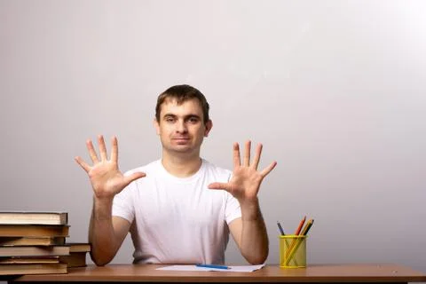 Young man sits at a table with a stack of books. Stock Photos
